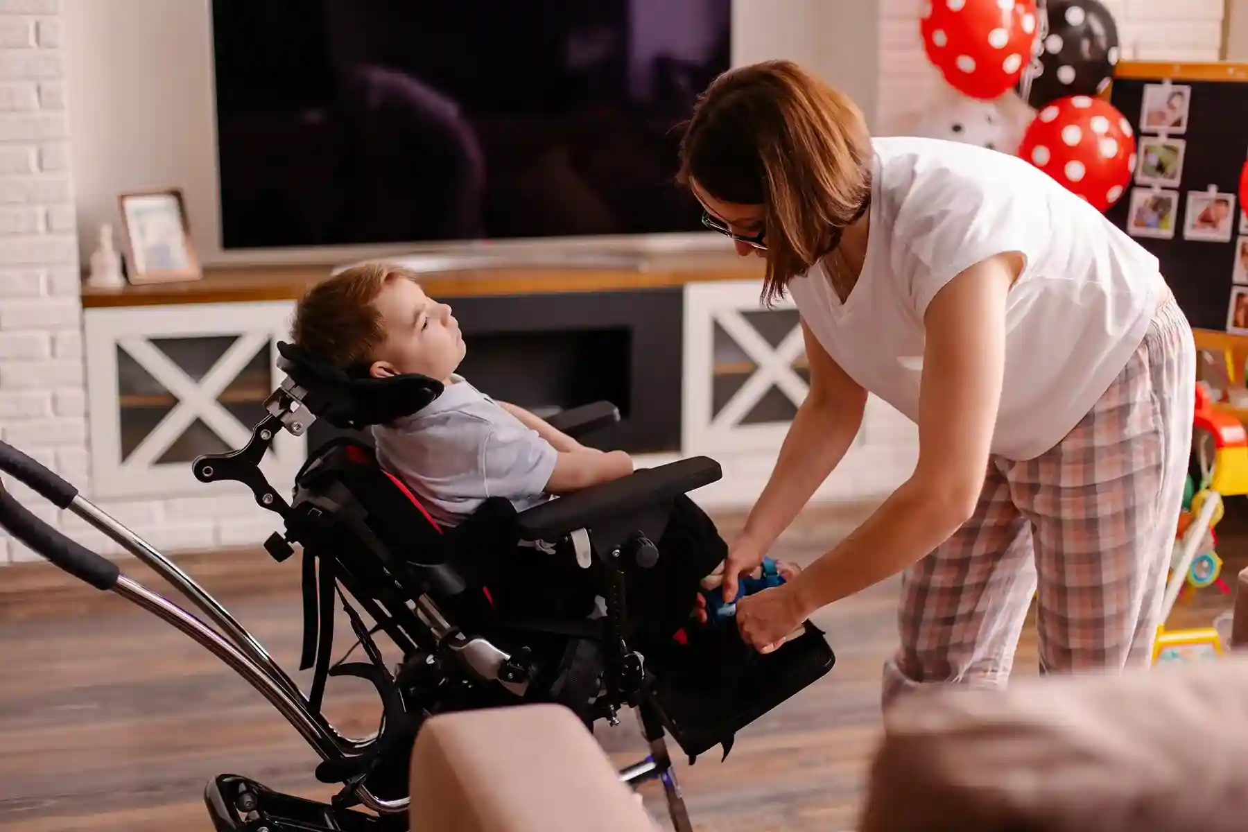 Caregiver helping a young child in a wheelchair at home