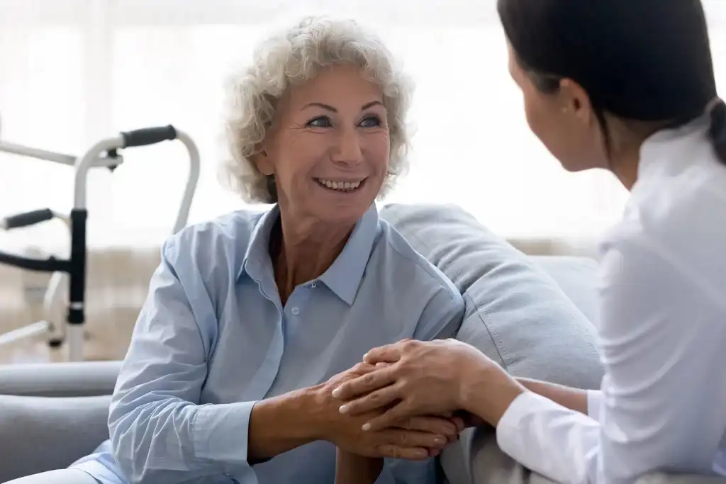 Smiling elderly woman receiving compassionate support from a caregiver at home, symbolising trust and aged care services.