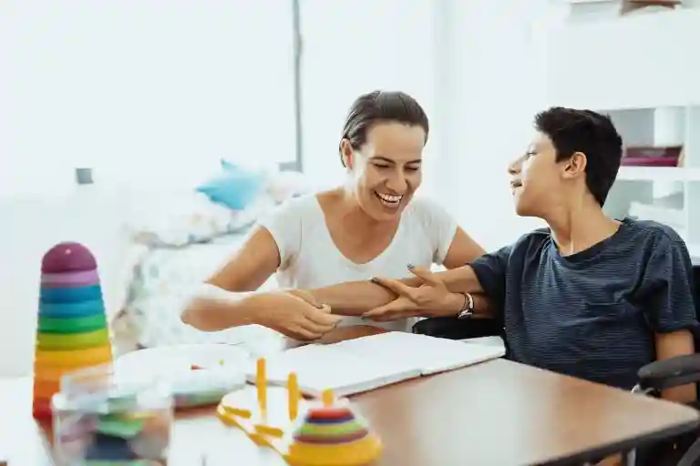 NDIS support worker assisting a child with a disability in a joyful therapy session, promoting engagement, communication skills, and inclusive care in Adelaide.
