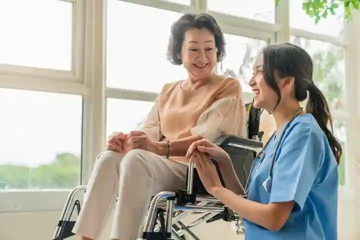 Smiling nurse providing compassionate wheelchair support to elderly woman in Adelaide respite care facility