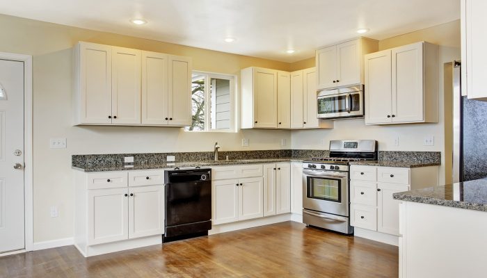 White new small simple classic American kitchen interior. Shiny hardwood floors.